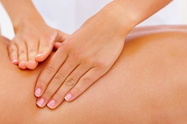 Eine Behandlerin legt ihre Hände zur Massage auf den Rücken einer Patientin